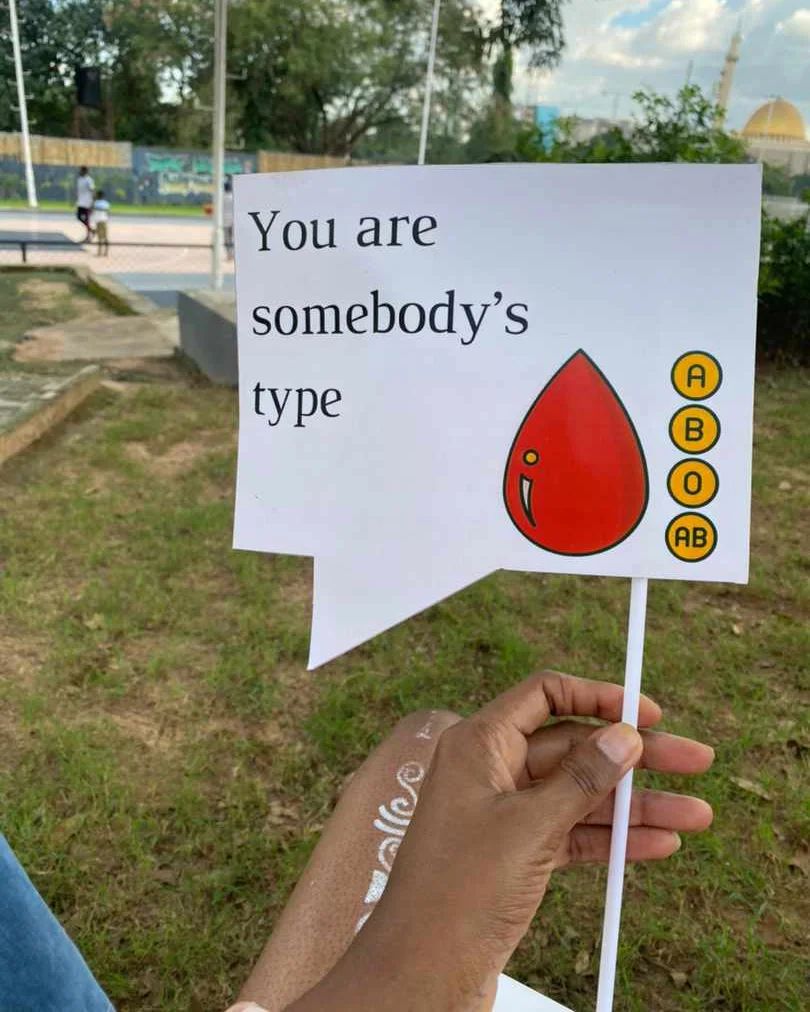 A Spark Blood lifeline in Nigeria holding a placard that reads 'You are somebody's type', a blood drop and A, B, O, AB tags.